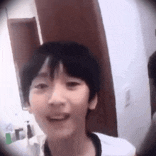 a young boy is smiling in a bathroom in front of a mirror .