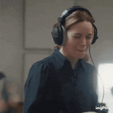 a woman is wearing headphones and smiling while looking at something