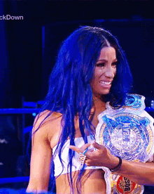 a woman with blue hair is holding a belt that says boss on it .