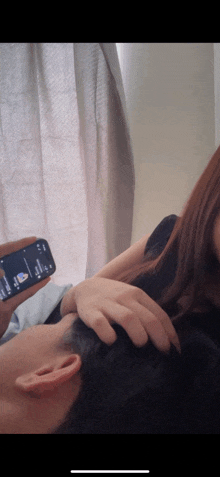 a woman is petting a man 's head while holding a phone that says google play