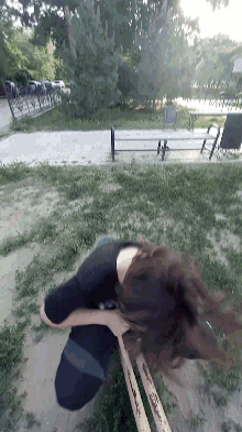 a woman in a black shirt is walking down a path in a park