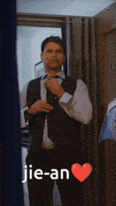 a man in a suit and tie is adjusting his tie with the words jie-an behind him