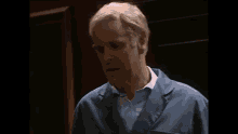 a man wearing a blue jacket and a white shirt is standing in a dark room .