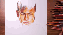 a drawing of a man 's face with colored pencils on a wooden table
