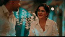a woman wearing glasses is smiling at a man