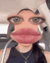 a woman wearing a black tank top and a silver necklace has a very large mouth and eyes