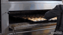 a person is taking a tray of cupcakes out of an oven that says made in animatica