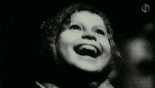 a black and white photo of a little girl laughing .