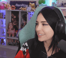 a woman wearing headphones is smiling in front of a renrize sign
