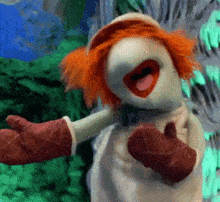 a puppet with red hair is wearing a white dress and red oven mitts