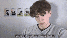a young man says you kind of look like a glowing david in front of a wall with cartoons on it .