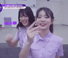 two girls are standing next to each other and one is making a heart shape with her finger