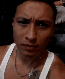a man wearing a white tank top has a tattoo on his chest