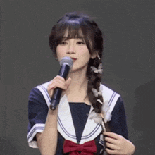 a girl in a sailor outfit is singing into a microphone .