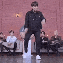 a man is dancing on a stage in front of a group of people sitting on a couch .