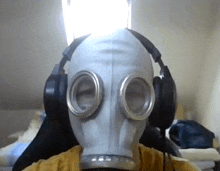 a person wearing a gas mask and headphones in front of a window