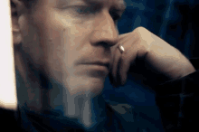 a close up of a man 's face with a ring on his finger