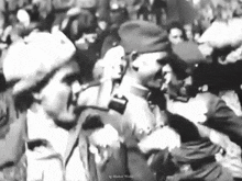 a black and white photo of a group of soldiers standing next to each other in a crowd .