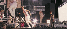 a man in a white tank top stands on a stage in front of a sign that says xxx