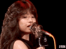 a close up of a woman singing into a microphone with the word syron on the bottom