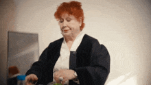 a woman with red hair is sitting at a table with a bottle of water