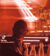 a man is standing in front of a bar with bottles and a tik tok sticker