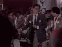 a group of men in suits and ties are dancing in a room with people sitting at tables .