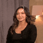 a woman with hearts on her forehead is wearing a black top and earrings