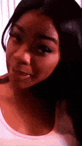 a close up of a woman 's face with long black hair and a white shirt .