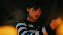 a woman wearing a black and white striped sweater is dancing in the dark .