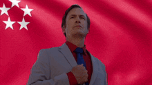 a man in a suit and tie is standing in front of a red background with white stars