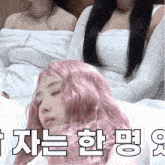 a woman with pink hair is laying down with her eyes closed