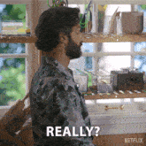 a man with a beard says really in front of a shelf