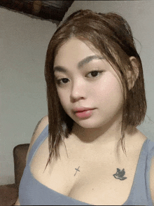a woman with a cross tattoo on her chest looks at the camera