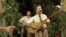 a man is playing a guitar while another man plays drums