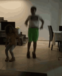 a boy and a girl are dancing in a living room with stairs in the background