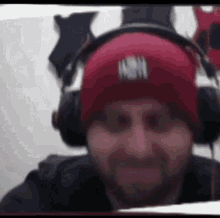 a man wearing a red beanie and headphones is smiling .