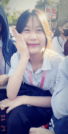 a girl in a white shirt with a pink lanyard around her neck is smiling for the camera on a photo taken on 8/6/21
