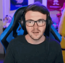 a man wearing headphones and glasses is sitting in a blue chair .