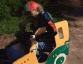 a man and a child are riding a toy truck at a playground .