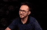 a man wearing glasses and a blue shirt is making a funny face .