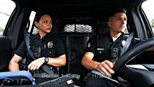 two police officers are sitting in a car with shopcam 7 a-100