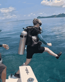 a scuba diver is jumping out of a boat into the water