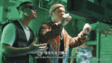 a gif from gifrun.com shows two men standing in front of a screen