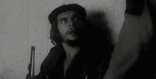 a black and white photo of che guevara holding a gun .