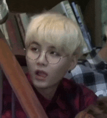 a young man with blonde hair and glasses is making a funny face .