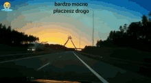 a car is driving down a highway at sunset and the words bardzo mocno placesz drogo are above it