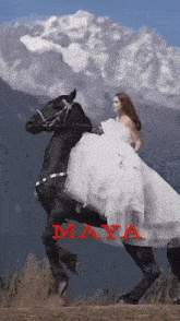 a woman in a white dress is riding a black horse with the name maya written on it