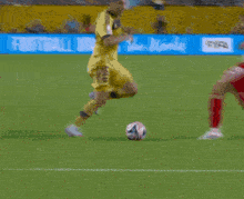 a soccer player is running on a field with a blue sign that says police in the background