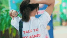 a woman wearing a white shirt that says talk to my hand on the back